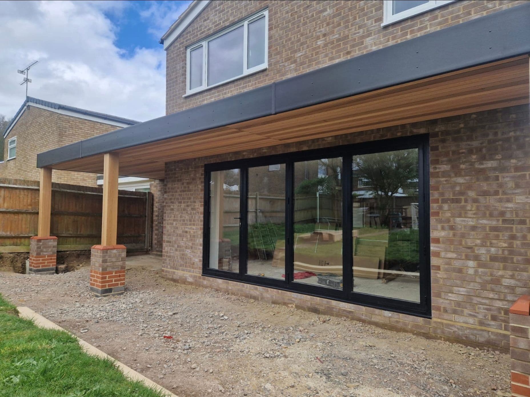 Single storey rear extension with anthracite bi-fold doors and timber soffit by DNR Build in Hertfordshire