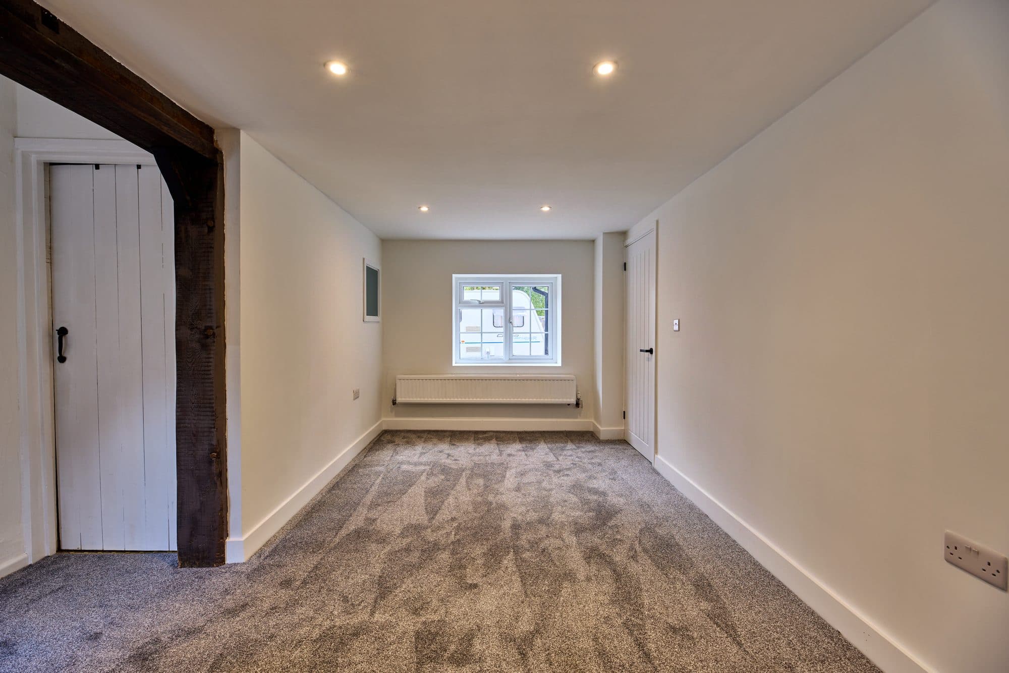 The renovated sitting room with new carpet, spotlights and an original timber post kept on show by DNR Build