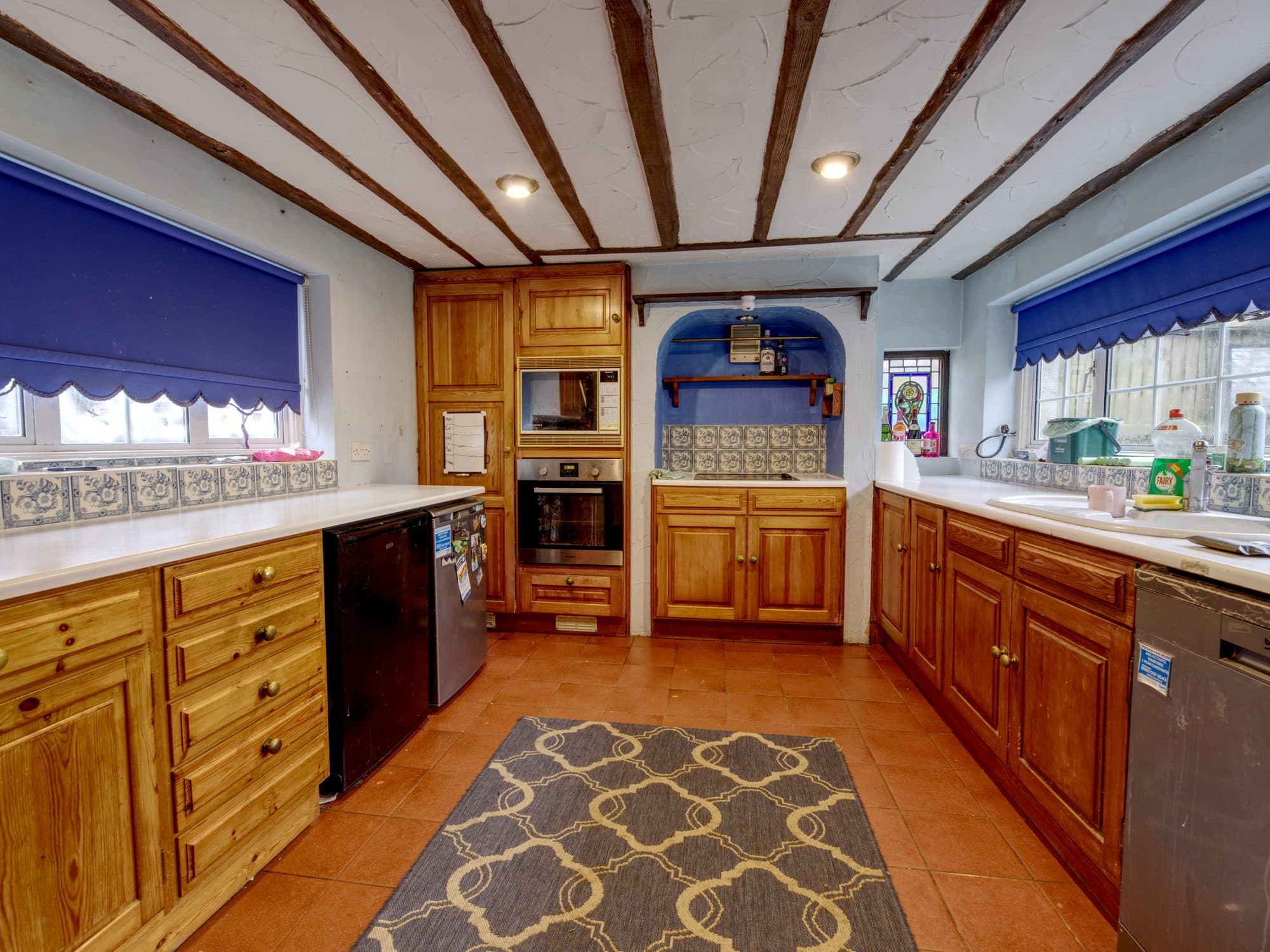 The old pine kitchen with a tiled floor and low beamed ceiling before the renovation