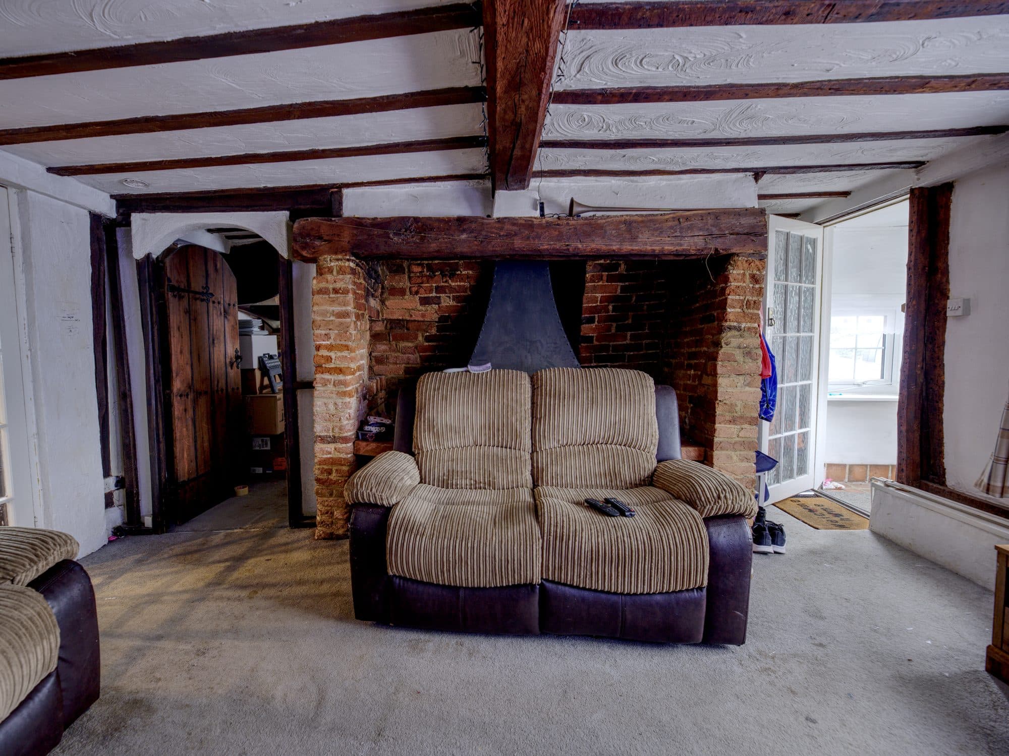 The old sitting room with a brick inglenook fireplace and dark beams