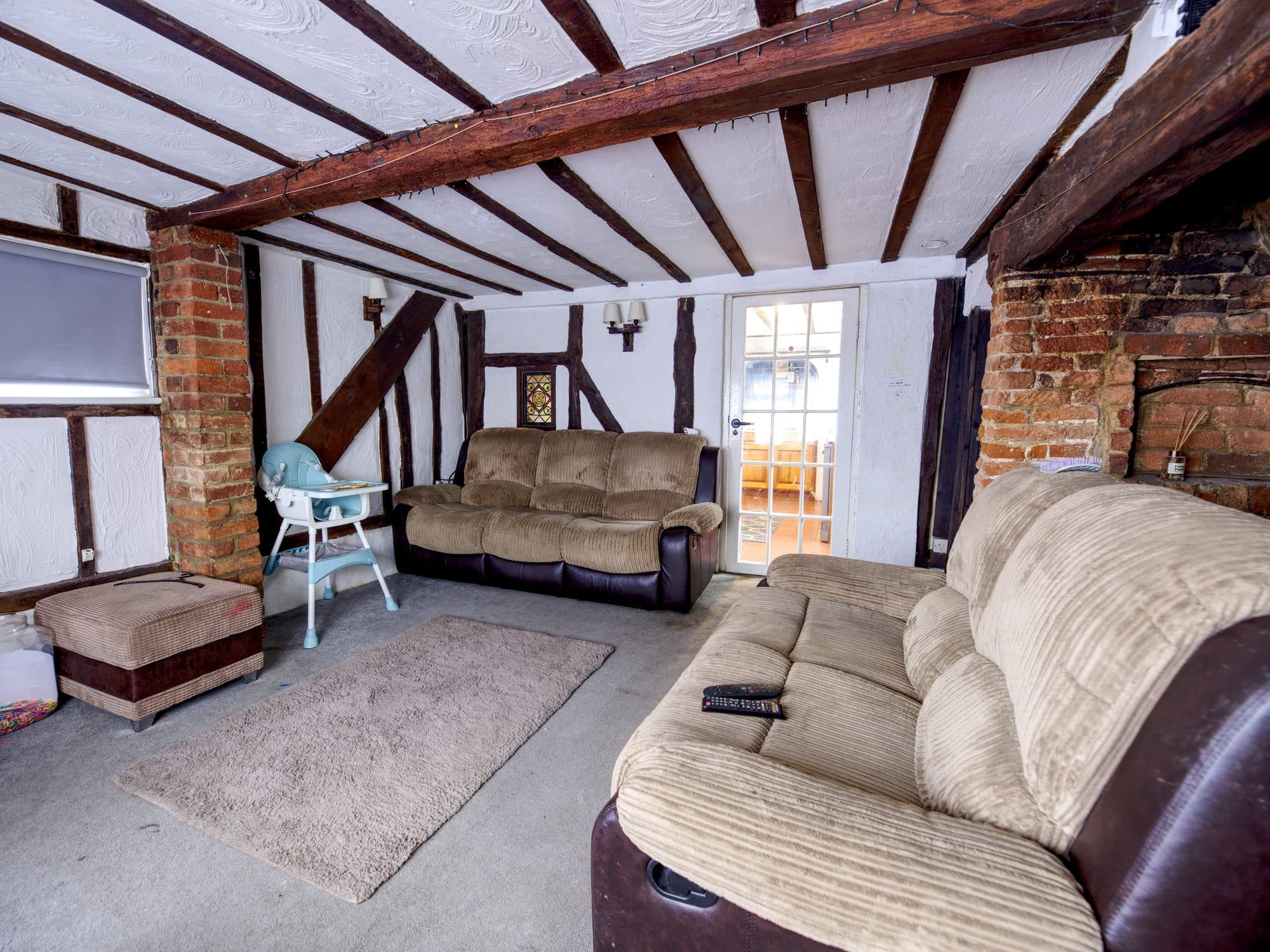 The old living room with exposed timber framing and worn carpet