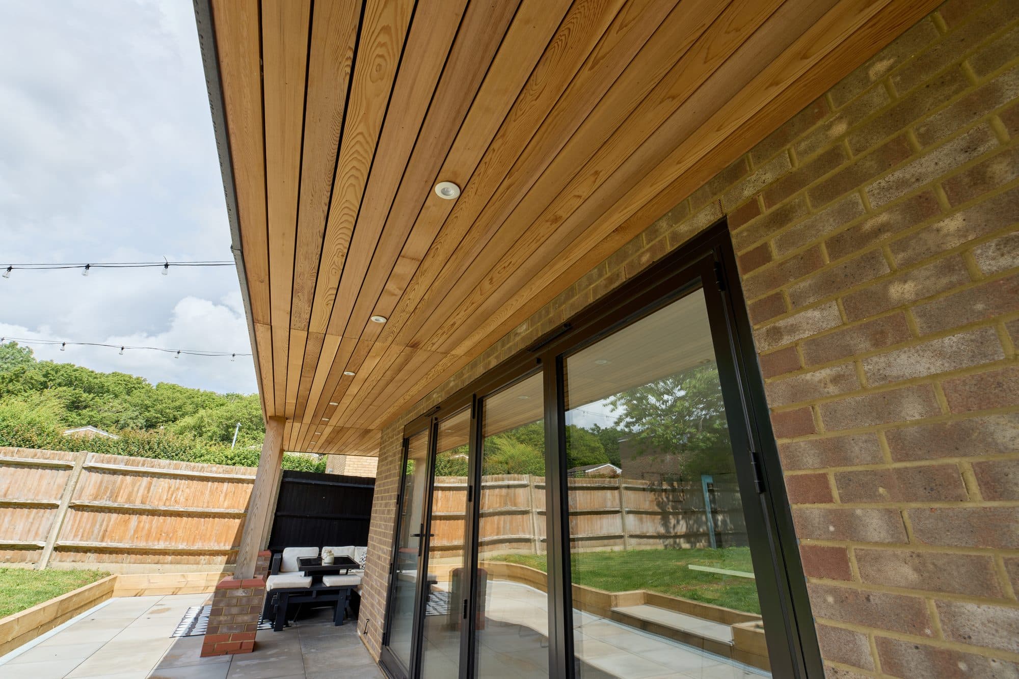 The finished cedar lined canopy with downlights over the bi-fold doors by DNR Build