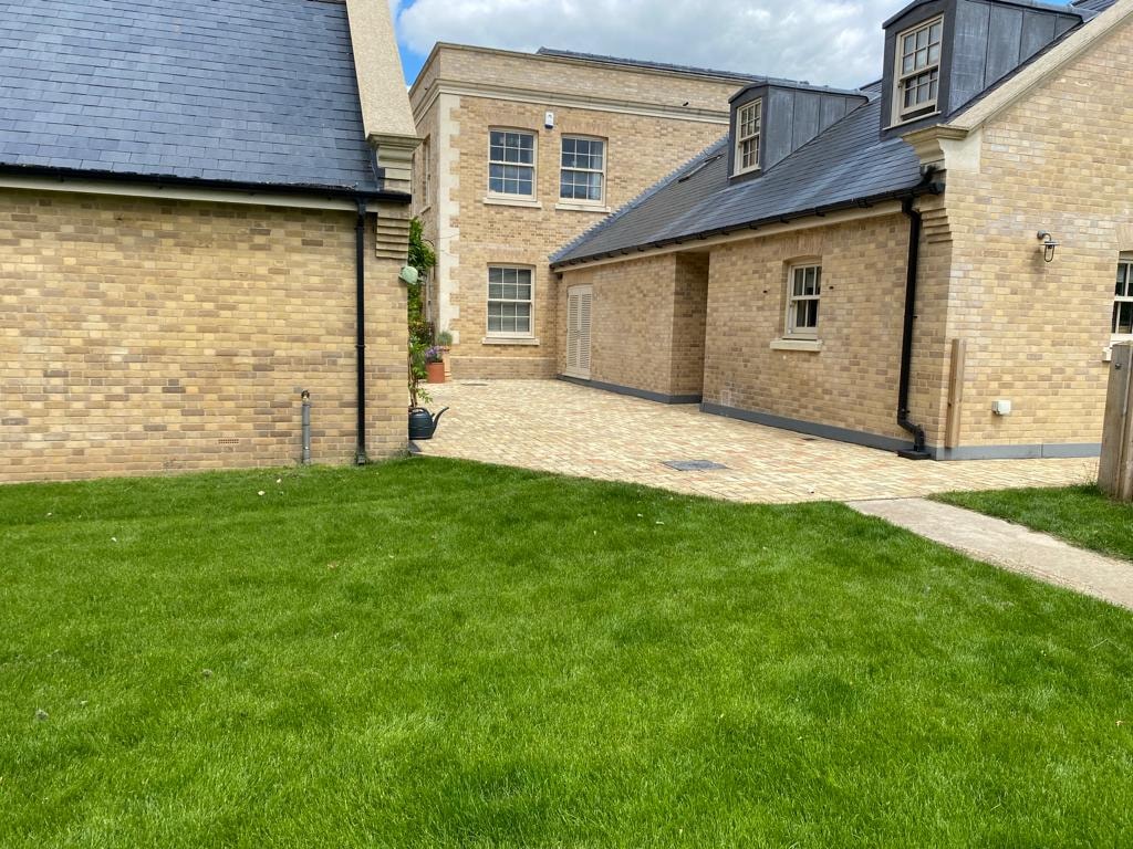Paved courtyard and lawn between the wings of the finished country house by DNR Build