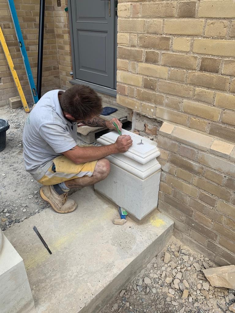 Stonemason hand carving a natural stone column plinth at the country house entrance by DNR Build