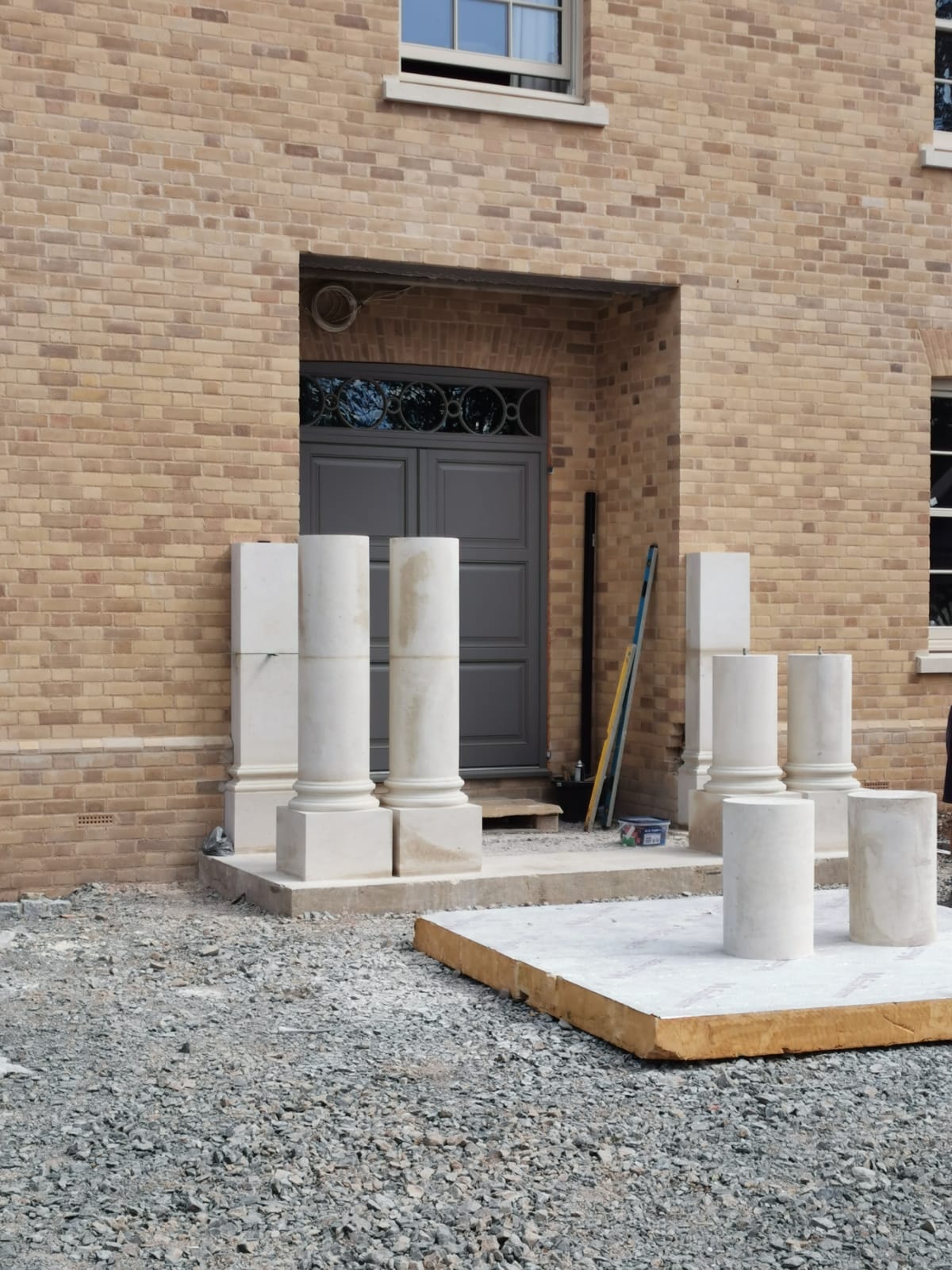 Carved stone columns set in place on the portico with cappings ready to fit by DNR Build