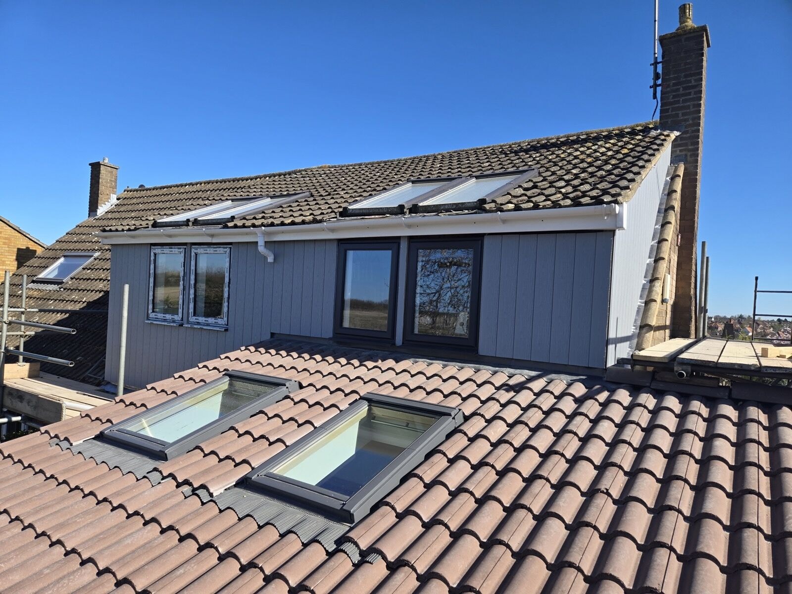 Completed double storey side extension with grey cladding, roof windows and matched roof tiles by DNR Build