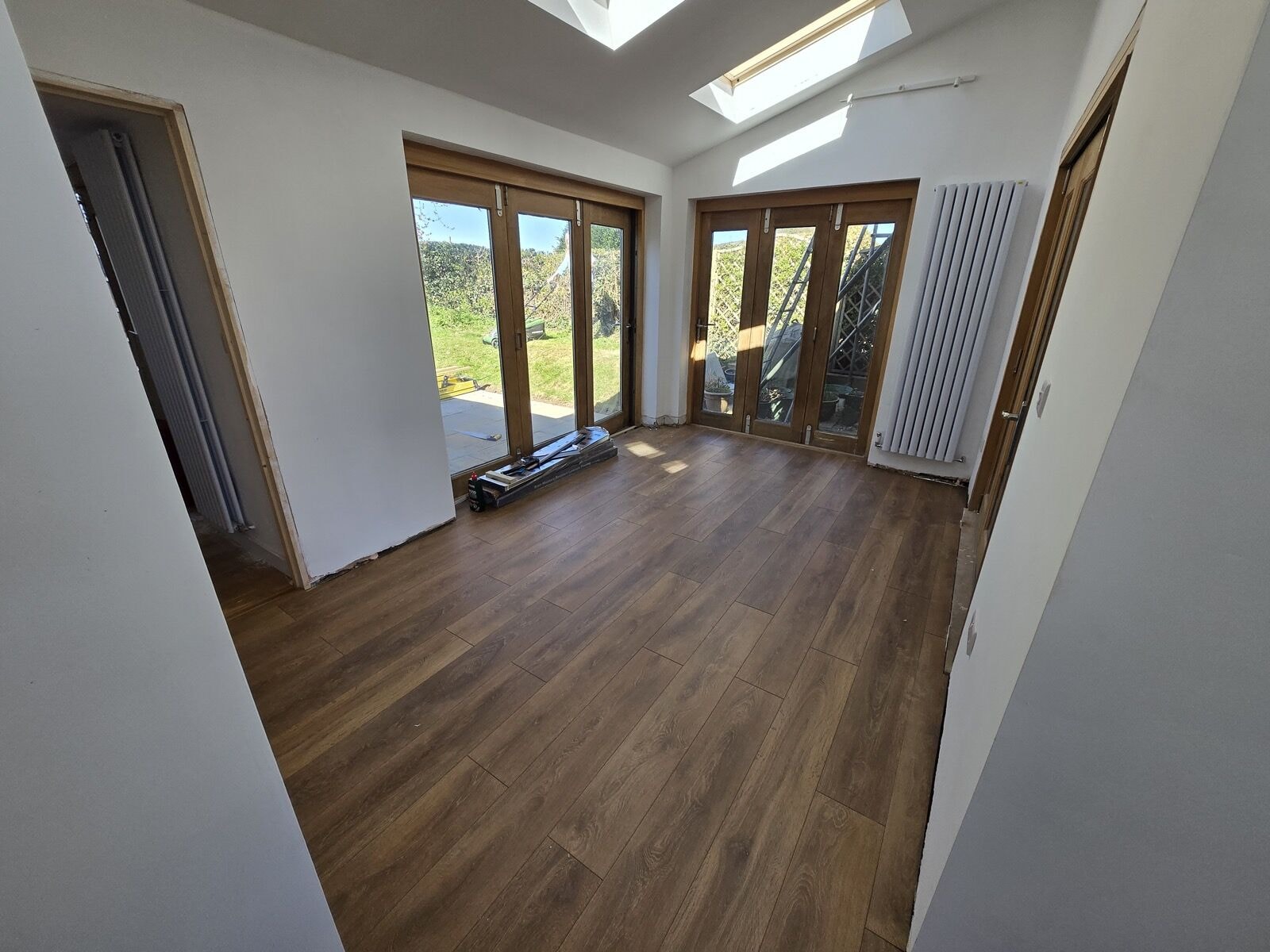 Finished interior of the extension with oak laminate flooring, bi-fold and French doors to the garden and a roof window by DNR Build