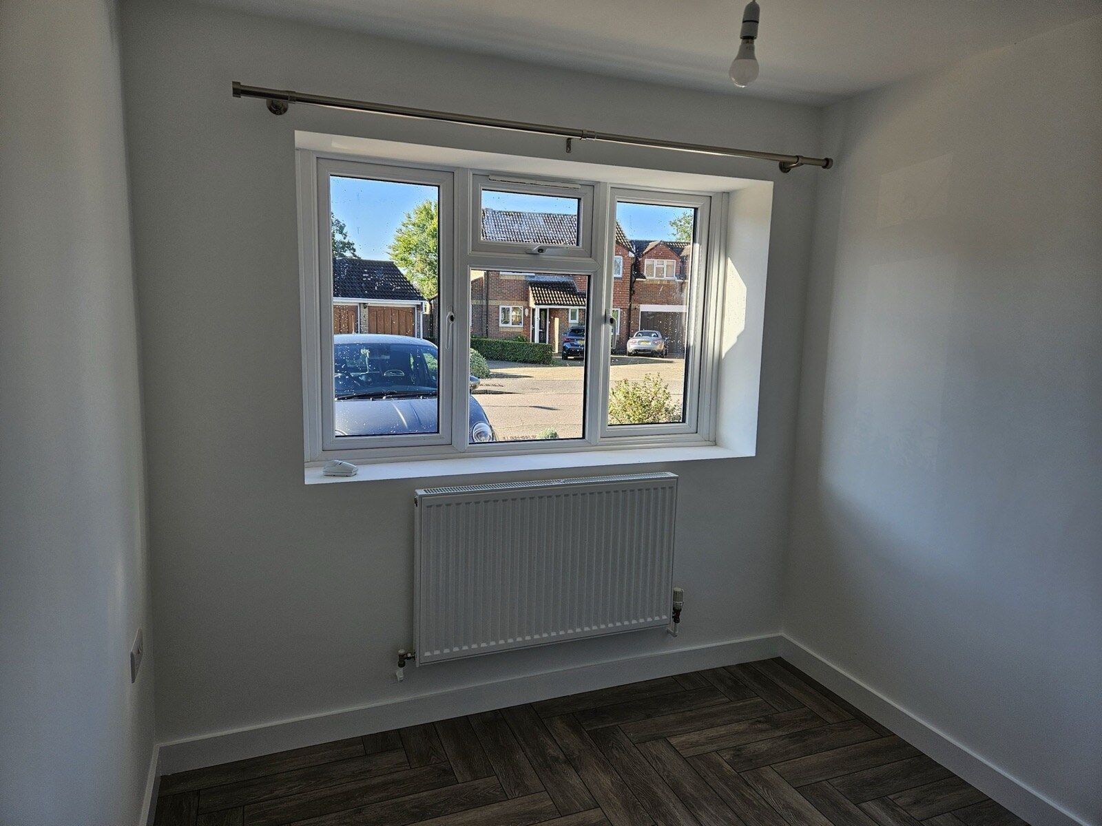 Newly finished room in the converted garage with a uPVC window, radiator and herringbone flooring by DNR Build