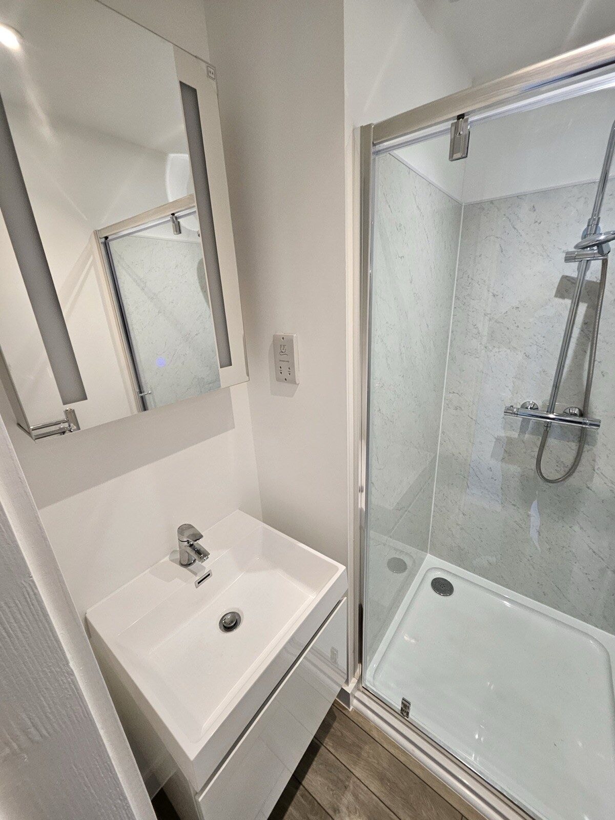 New shower room with a wall hung vanity basin, mirror and walk in shower by DNR Build