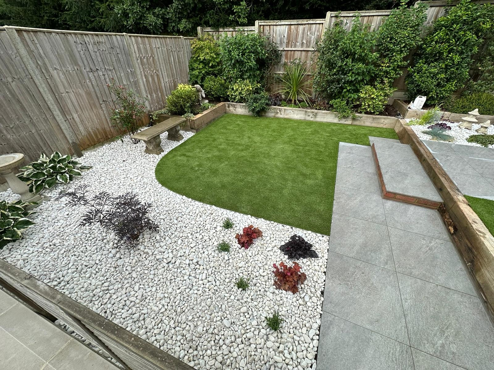 Pebble bed with specimen planting curving around the new lawn in the finished garden by DNR Build