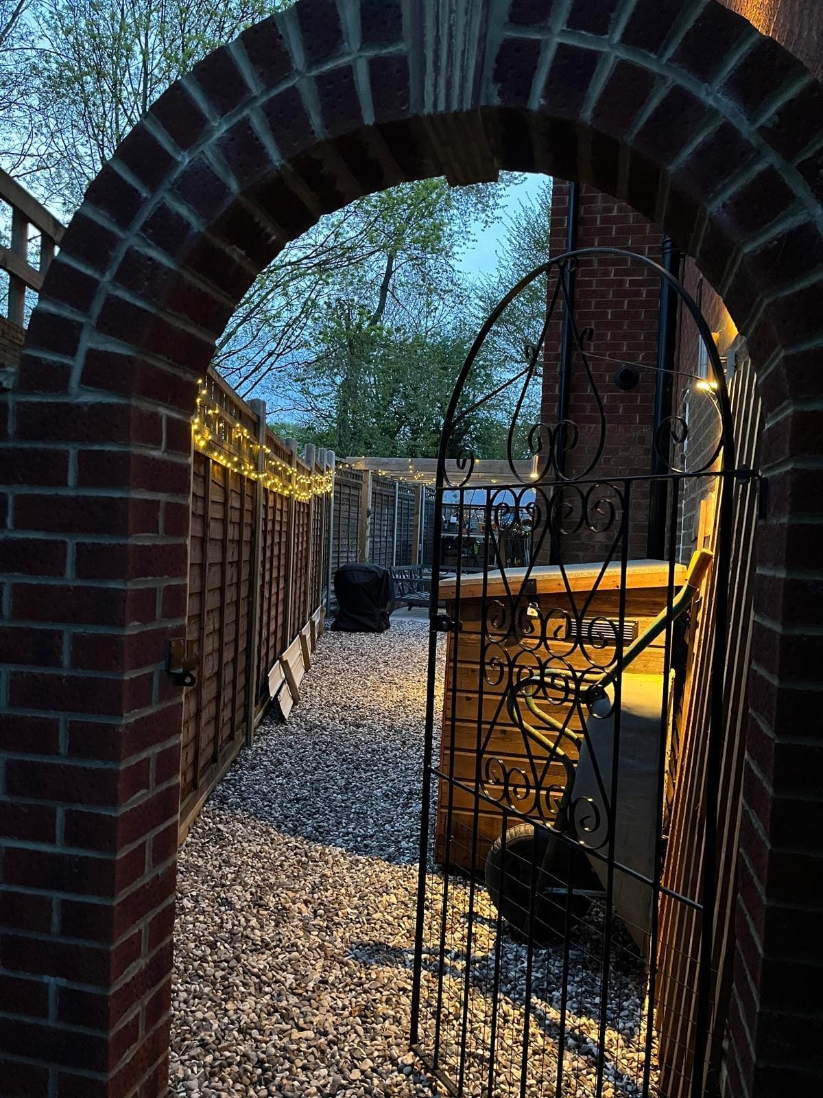 The brick archway and open gate leading down the side of the house to the garden by DNR Build