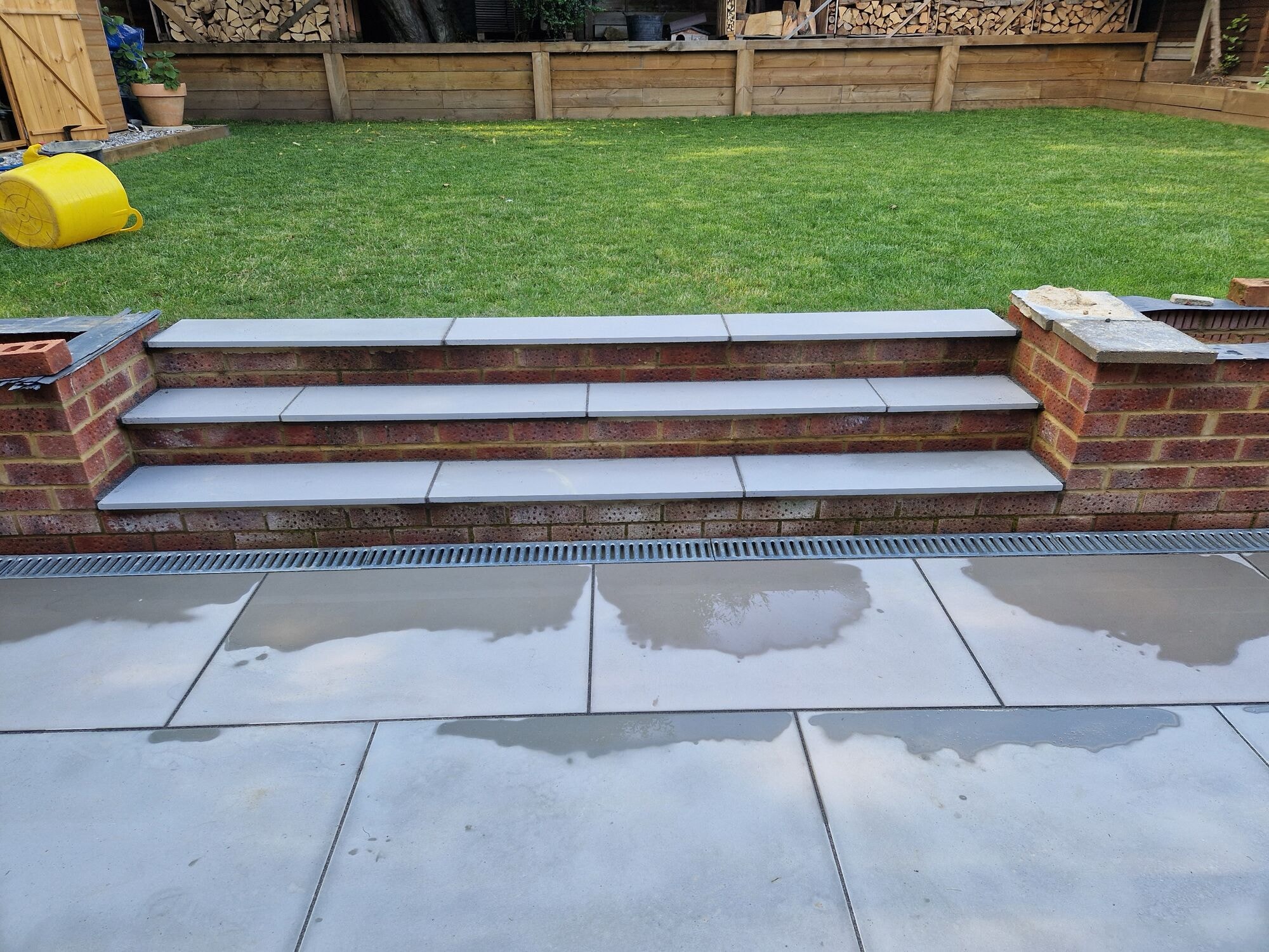 New porcelain steps and brick retaining wall leading up to the finished lawn by DNR Build