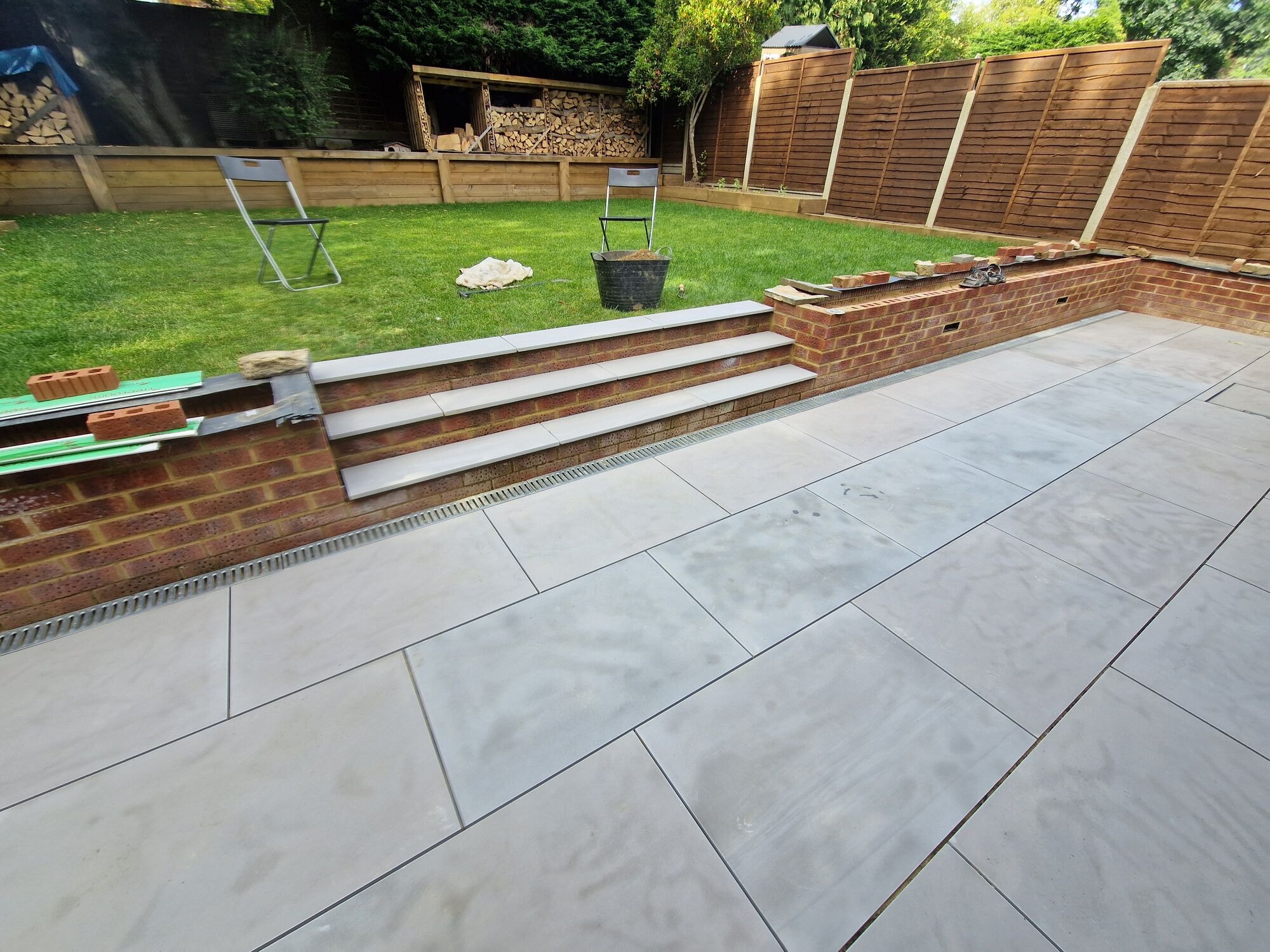 New porcelain patio and steps with the brick retaining wall in the finished garden by DNR Build