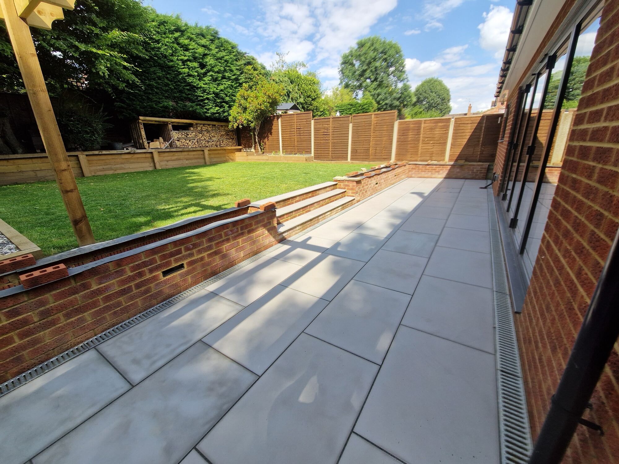 The finished patio and steps with the lawn in full sun by DNR Build