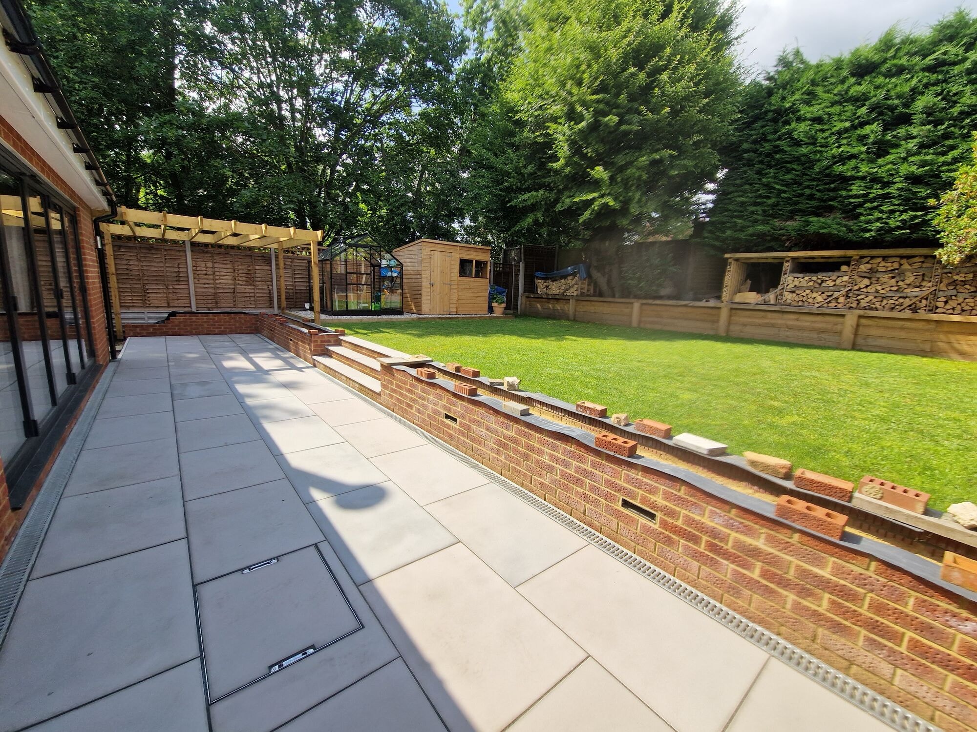 Porcelain patio running along the rear of the house to the bi-fold doors by DNR Build