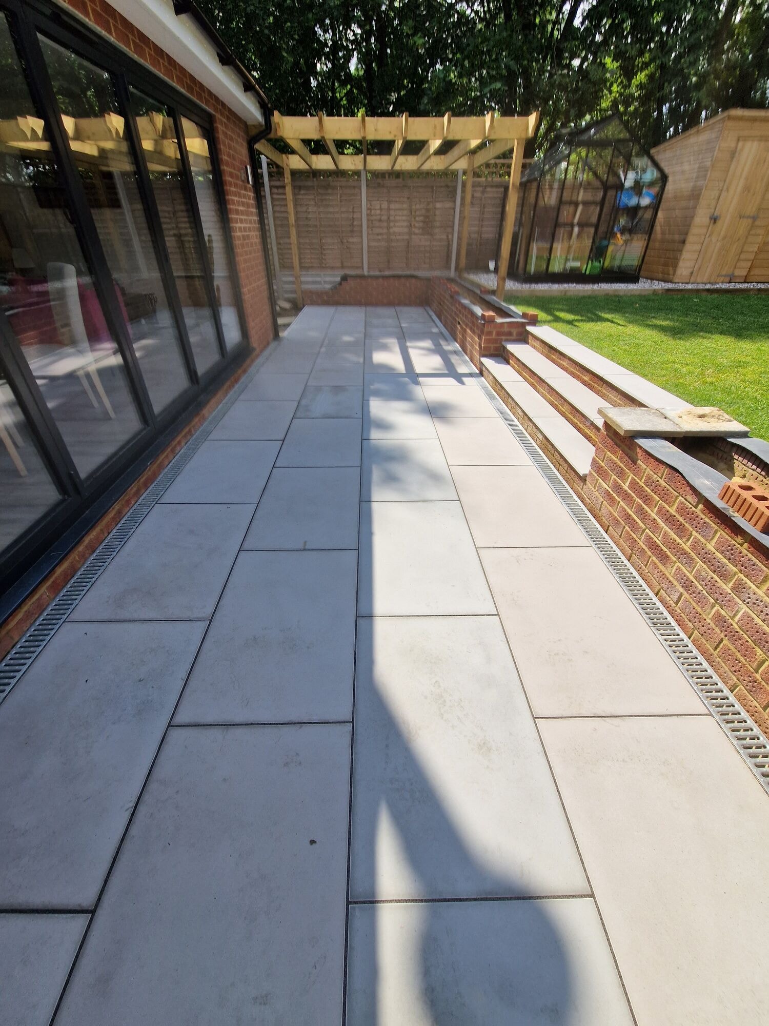 The patio path along the bi-fold doors under the new timber pergola by DNR Build