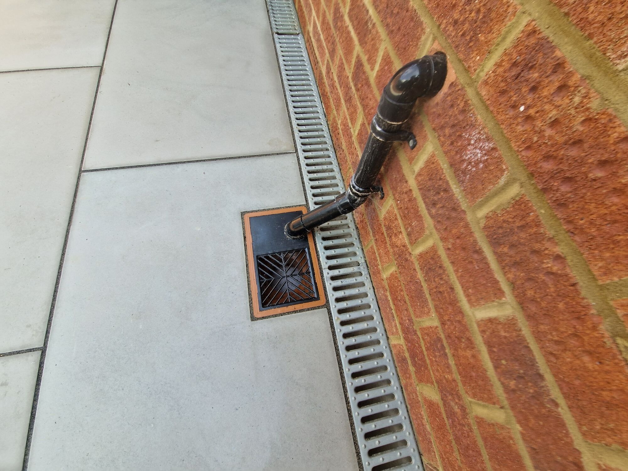 Brick retaining wall with a drainage channel detail beside the new patio by DNR Build