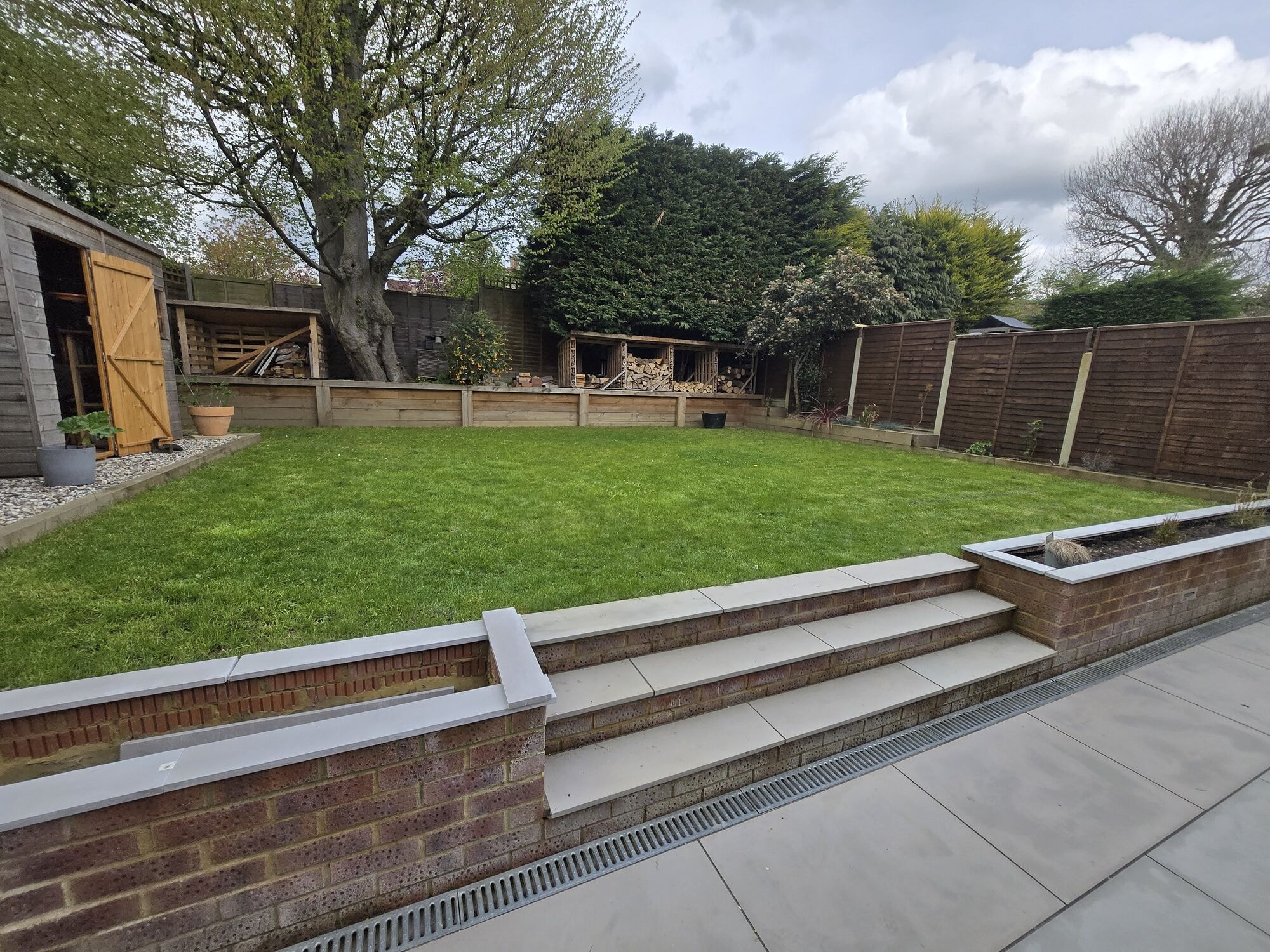 The established garden with the patio, lawn, log stores and planting by DNR Build