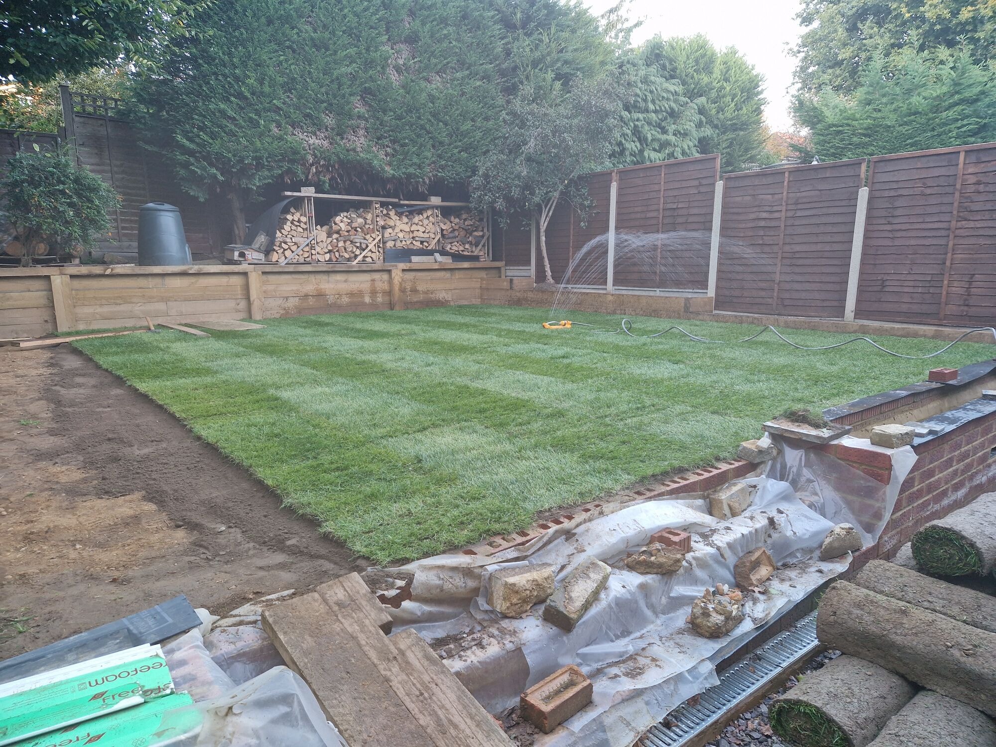 Fresh turf being laid across the garden against the new brick retaining wall by DNR Build