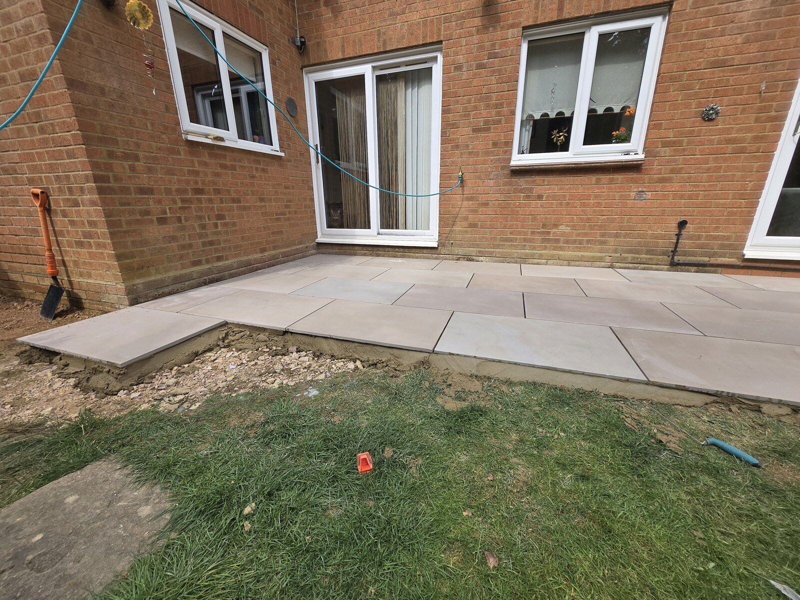Newly laid sandstone patio against the rear of the house with the lawn being reinstated by DNR Build