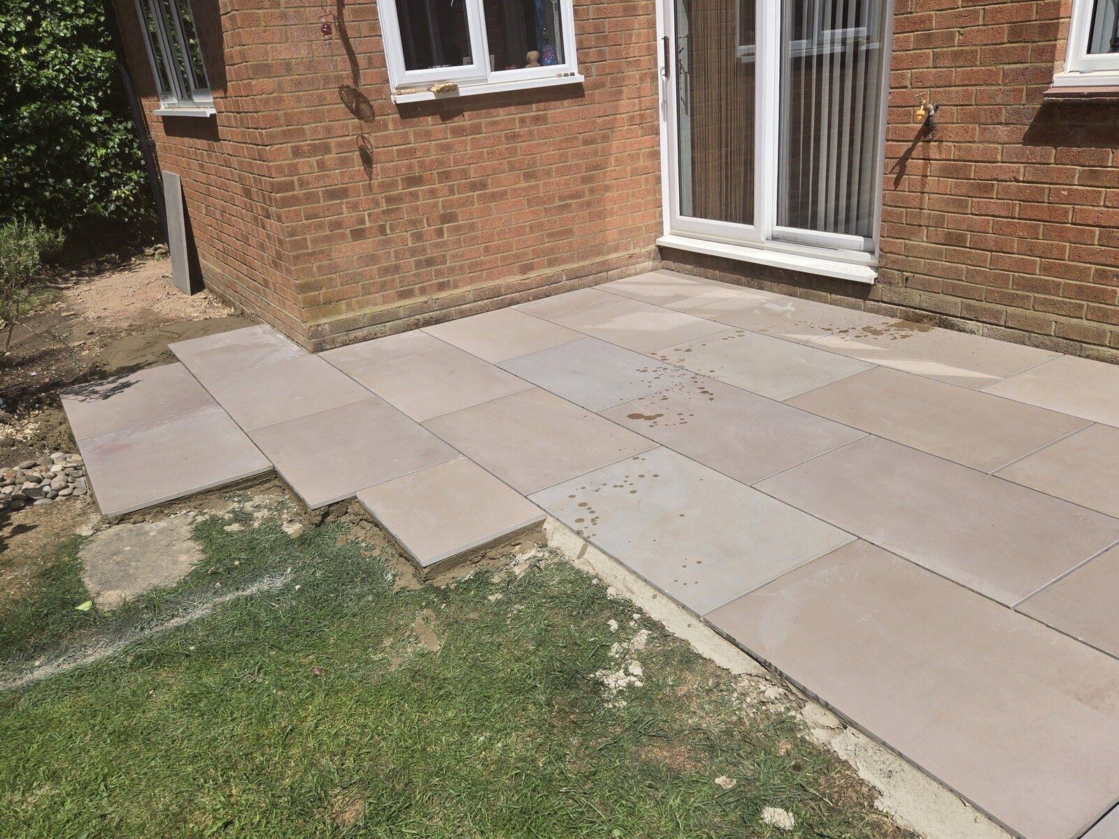 Sandstone paving laid up to the rear doors with the patio edge meeting the lawn by DNR Build