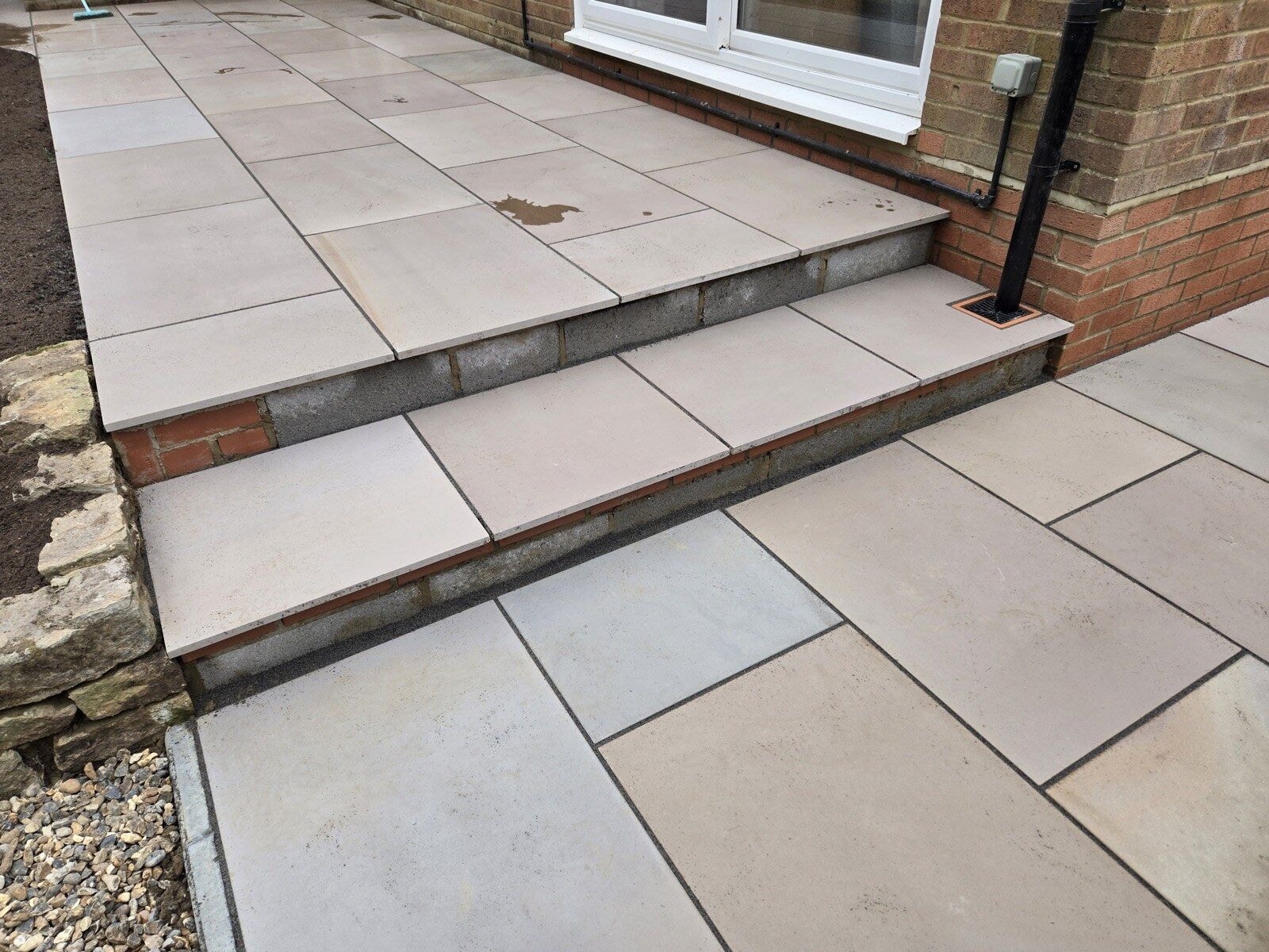 Wide sandstone steps and patio levels finished against the house with a drain detail by DNR Build