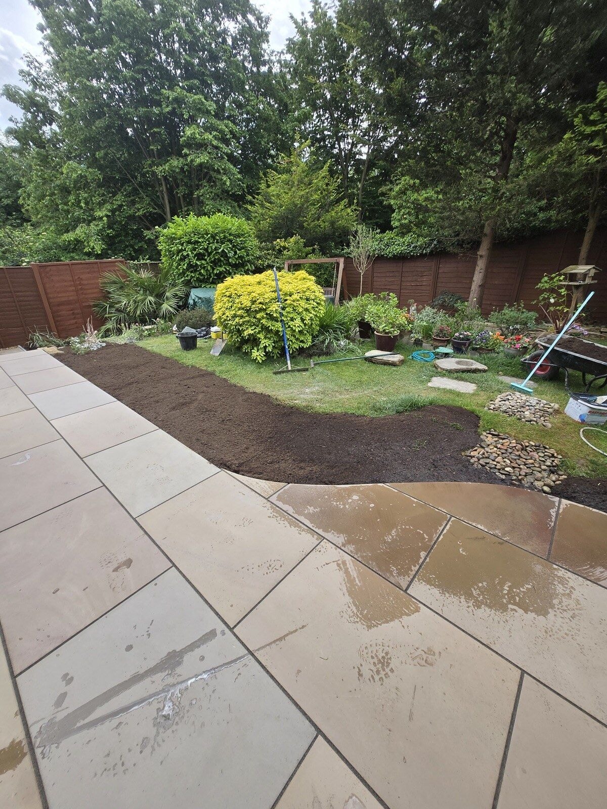 New sandstone patio with a curved border to the lawn and replanted garden beyond by DNR Build