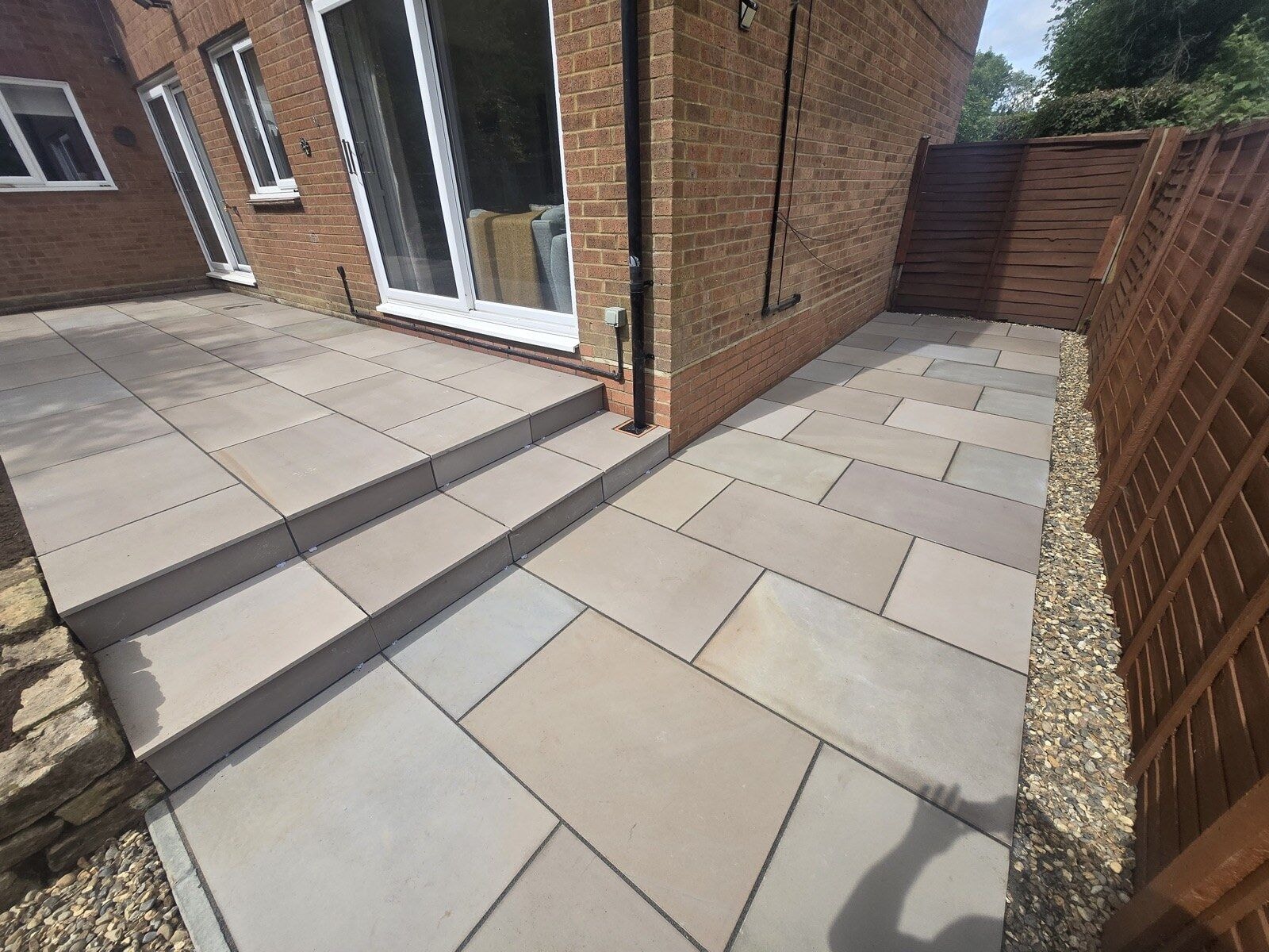 Finished sandstone patio with steps, gravel borders and timber fencing by DNR Build