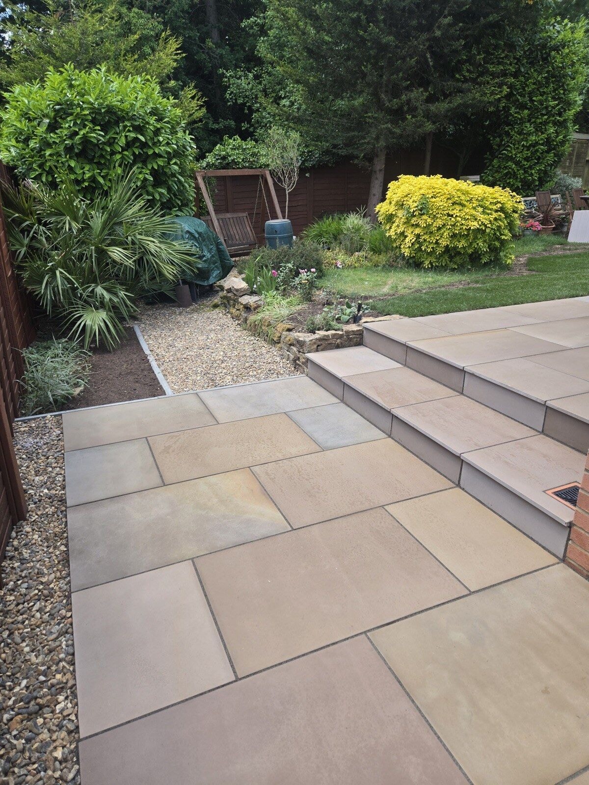 Finished sandstone patio and steps with a planted garden, gravel beds and new lawn by DNR Build