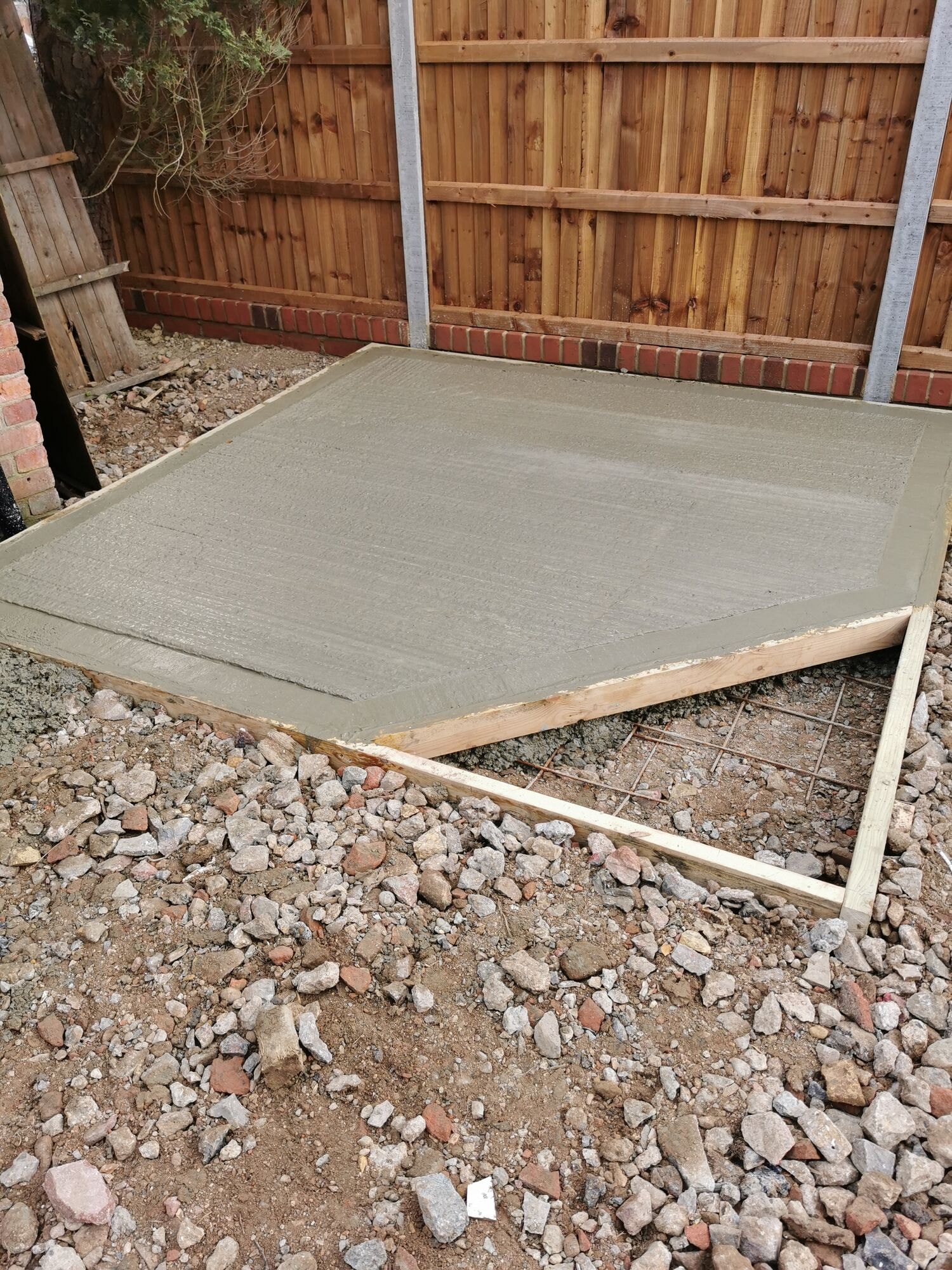 A reinforced concrete base laid in the corner of the garden ready for the shed by DNR Build