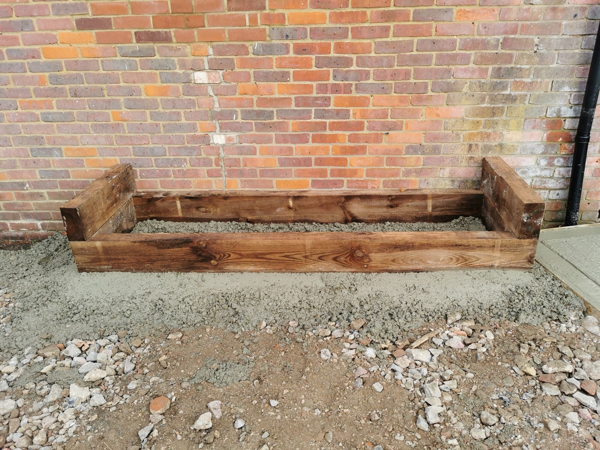 Oak sleeper raised bed set into concrete against the brick wall of the house by DNR Build