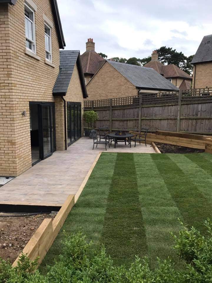 The striped new lawn enclosed by sleeper raised beds against the brick boundary walls by DNR Build