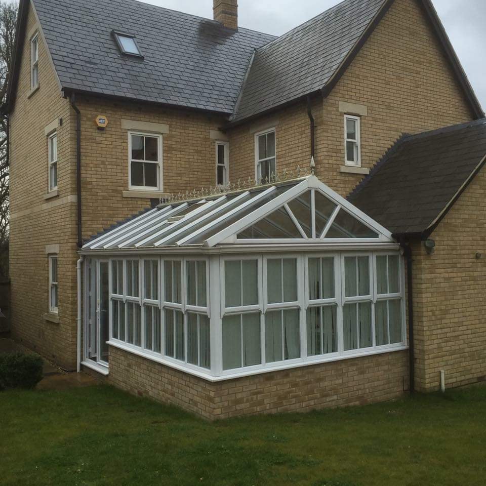 A glazed conservatory on the rear of the home overlooking the garden by DNR Build