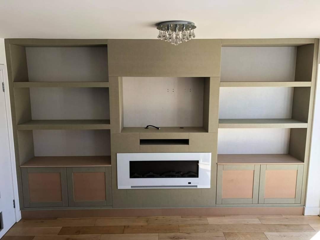 The fitted media unit with shelving and cabinets either side of the central fire and TV recess by DNR Build