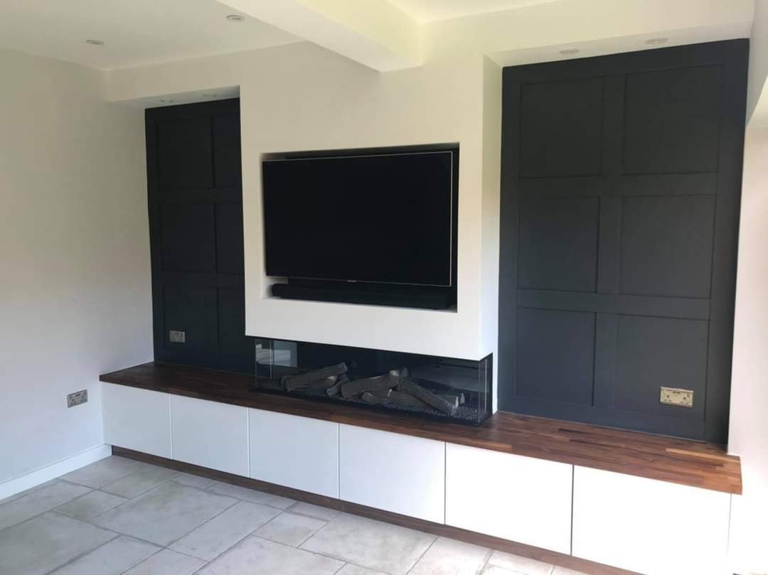 The finished panelled media wall with deep black panelling either side of the recessed television by DNR Build