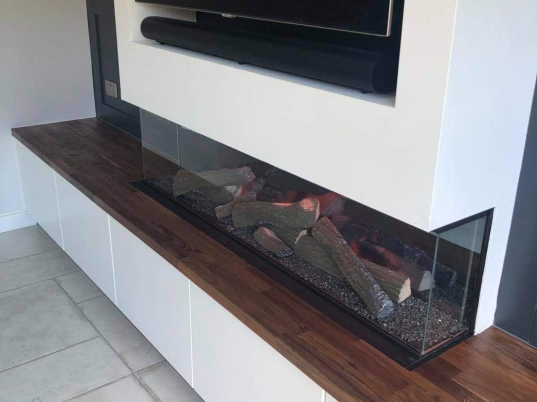 Close up of the long glass fronted log effect fire set into the walnut worktop by DNR Build