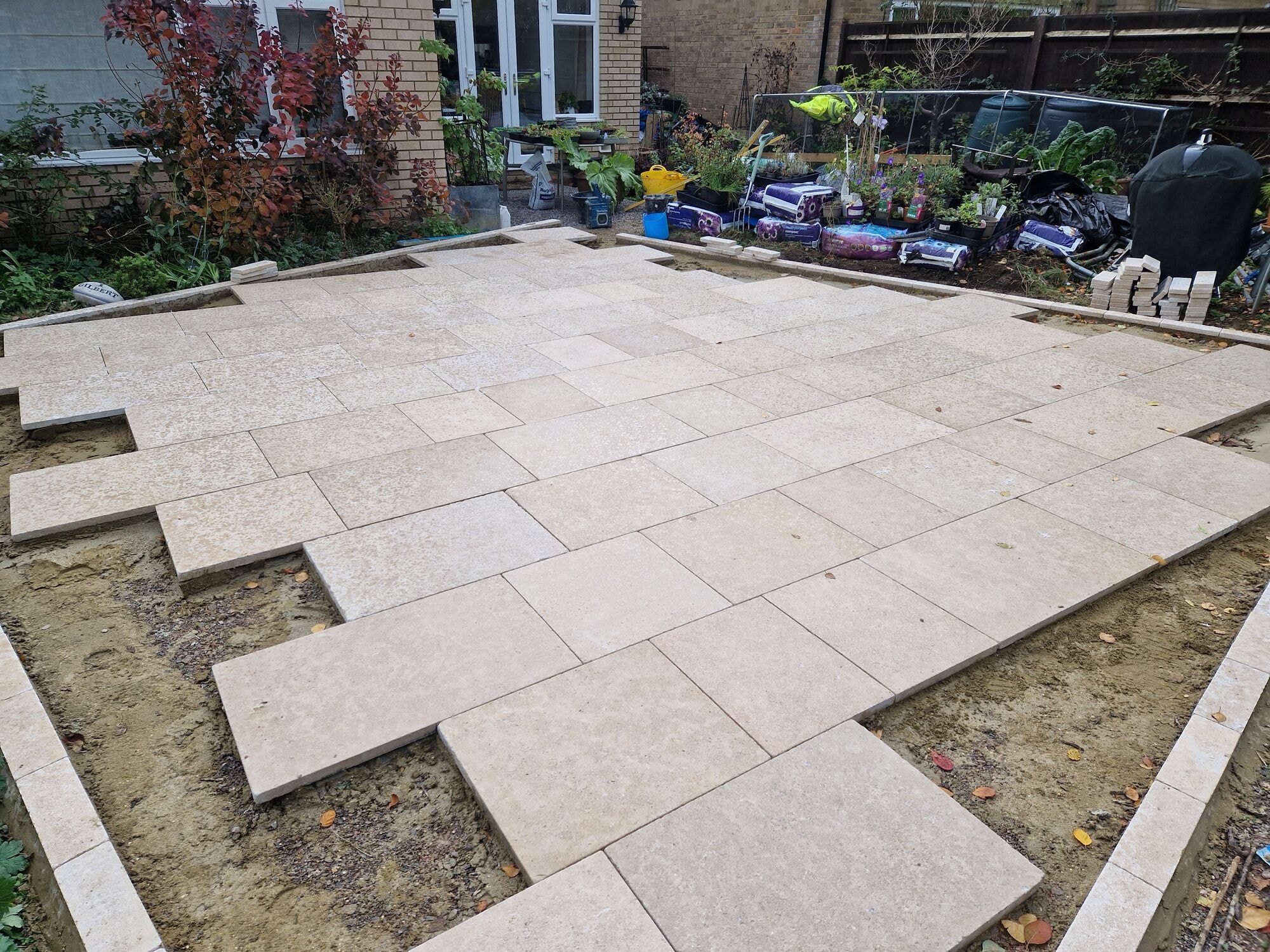 The new tumbled travertine patio part laid across the garden with the base prepared by DNR Build