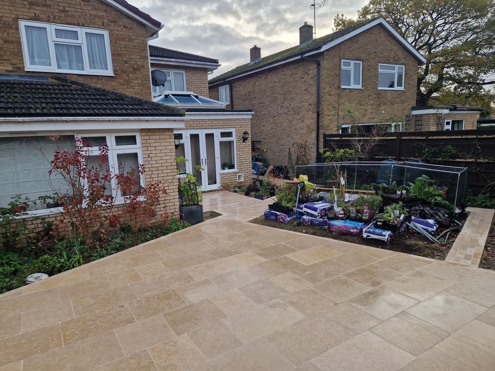 The finished travertine patio wrapping from the house French doors out across the garden by DNR Build