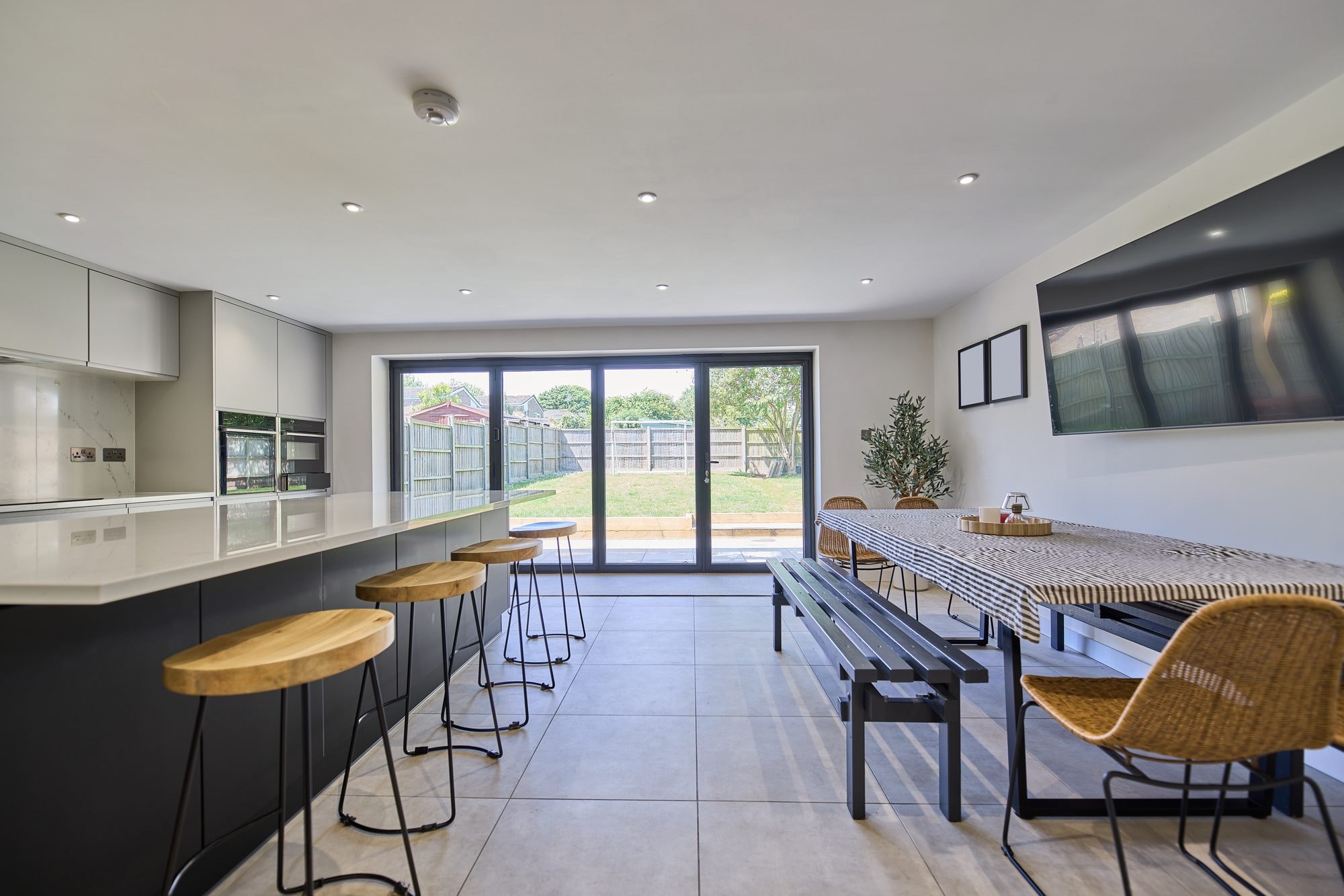 The finished open plan kitchen and dining room with a large island and bi-fold doors at the Stevenage home by DNR Build (6 of 6)