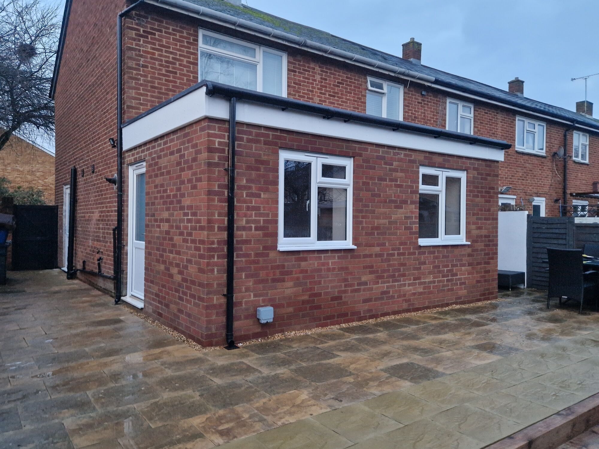 Corner view of the finished single storey extension with a new sandstone patio by DNR Build