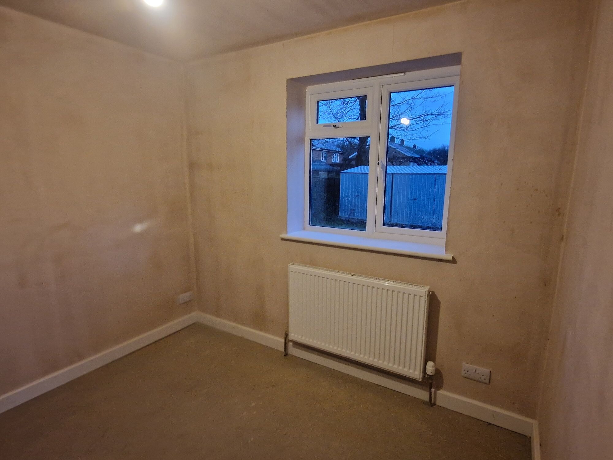 Newly plastered room in the extension with a new window and radiator by DNR Build