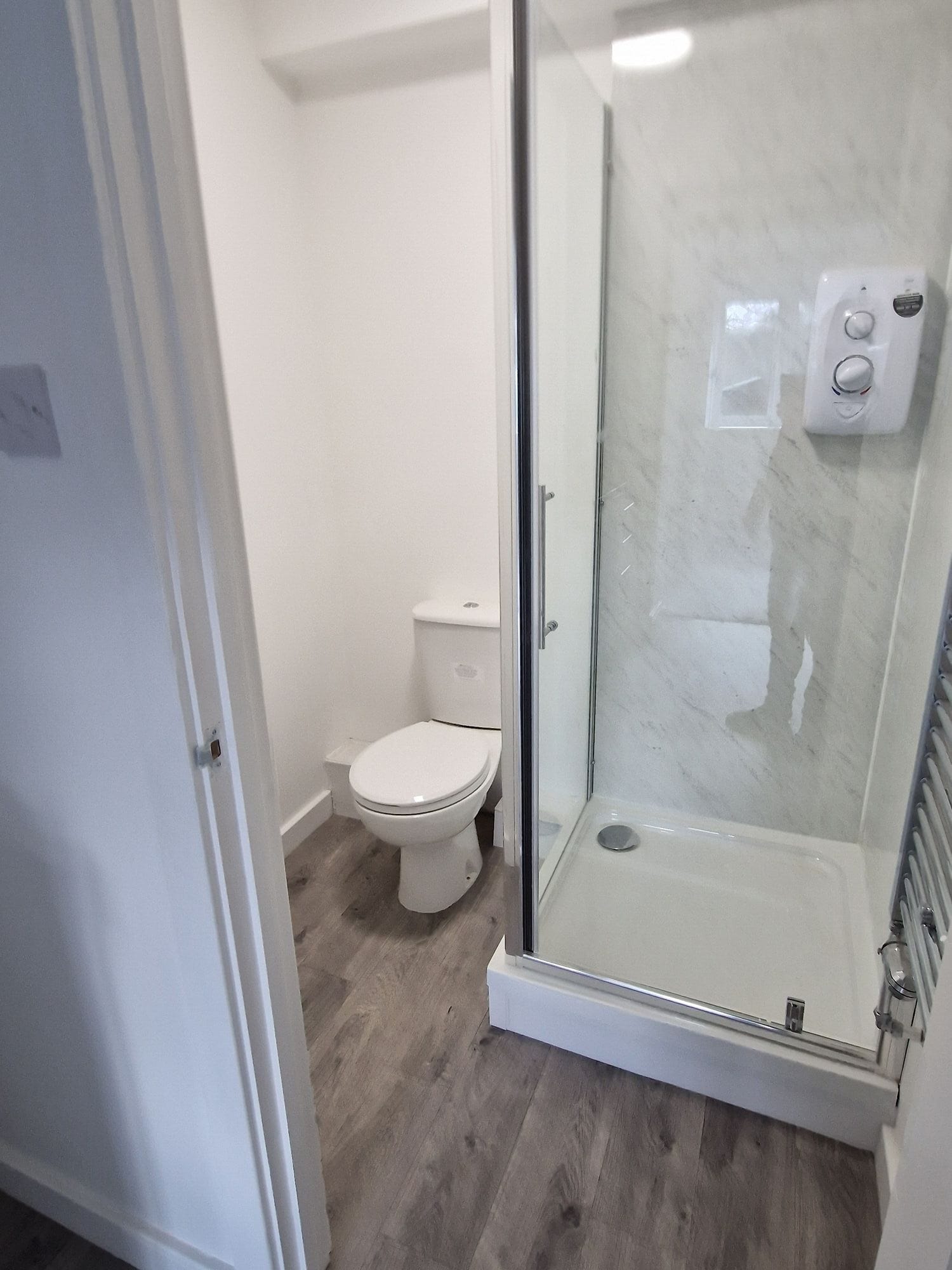 Finished shower room with marble effect panels, a shower enclosure and WC by DNR Build