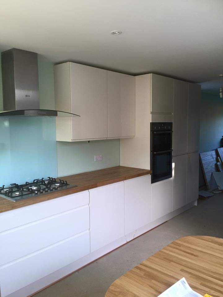 Kitchen units, oven tower and oak worktops in place with the glass splashback by DNR Build